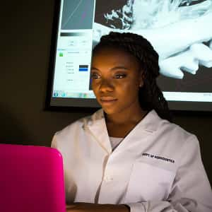 Woman in dental coat looking at laptop