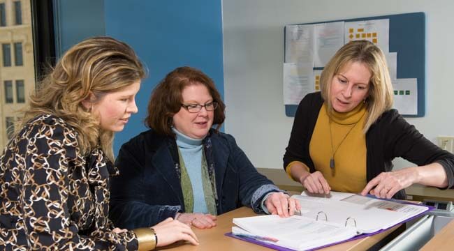 Three women looking at notebook