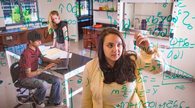 student drawing equations on board