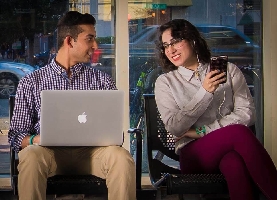 Man on laptop and woman on phone talking together