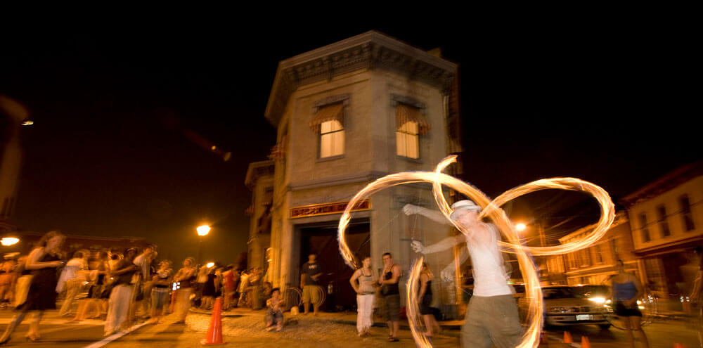 Man twirling flames outside at night during First Fridays