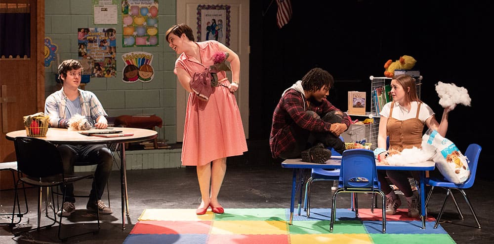 Four students performing on stage set to look like children