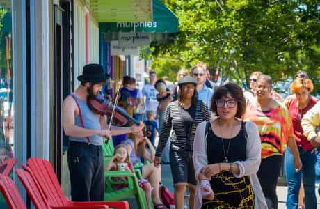 Pedestrians walking past musician playing violin on Cary St.