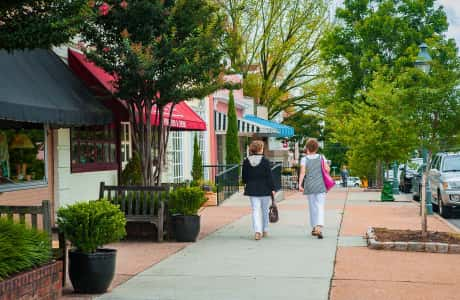 Two women walking past shops