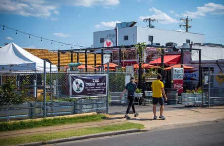 Two people walking past outdoor dining area at restaurant