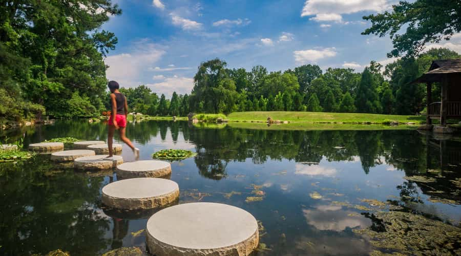  Woman walking over stepping stones in pond