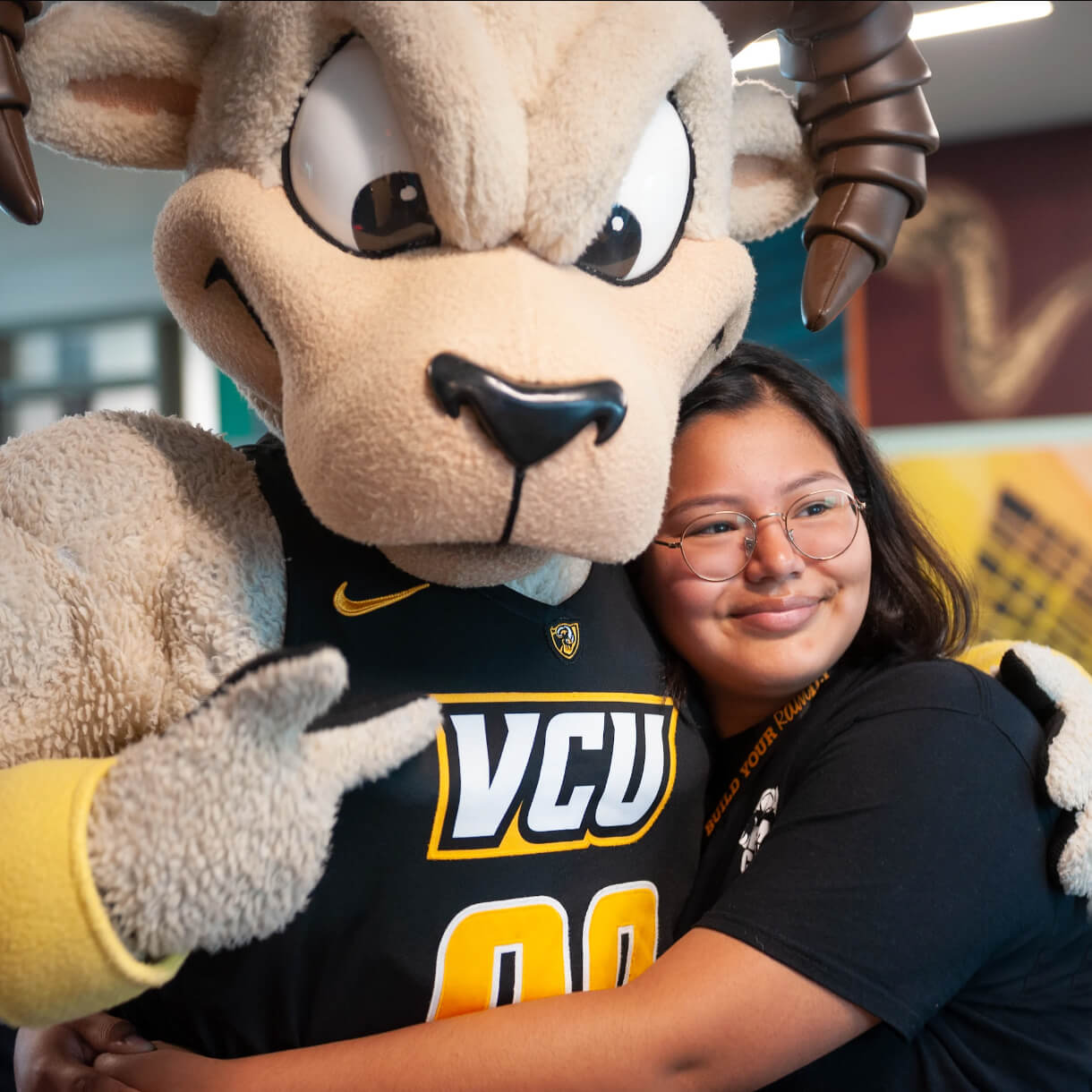 Mascot Rodney the Ram hugging a student.